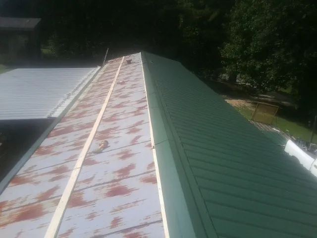Old rusted panels beside newly installed green metal roofing — Wind Damage Roof Repair by Roofing Brothers in Wilmot