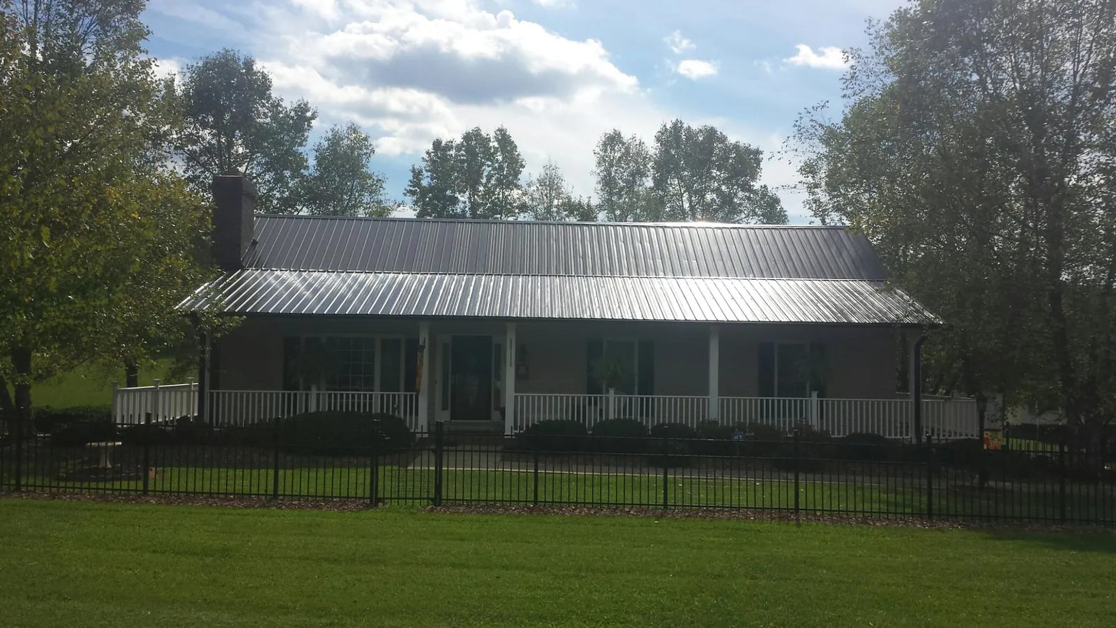 Gray metal roof on a brick ranch with a full width front porch — Gutter Guard Installation work by our crew in Wilmot