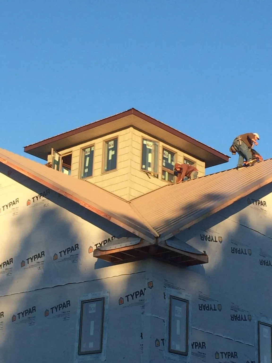 Roofers working around a rooftop cupola on a new metal roof at sunset — Roof Waterproofing in Wilmot by Roofing Brothers